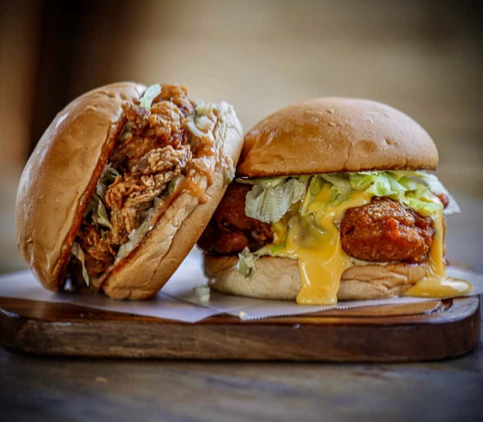 Two burgers with fried chicken and pulled pork