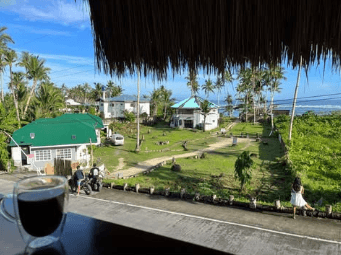 Glass of iced coffee on a balcony overlooking palms and fields