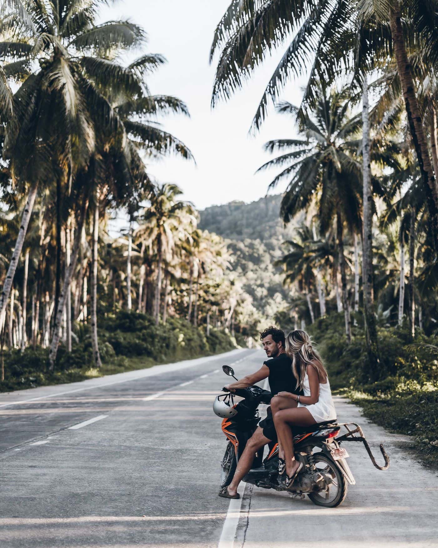 Couple on a motorbike on a palm-lined road in Siargao