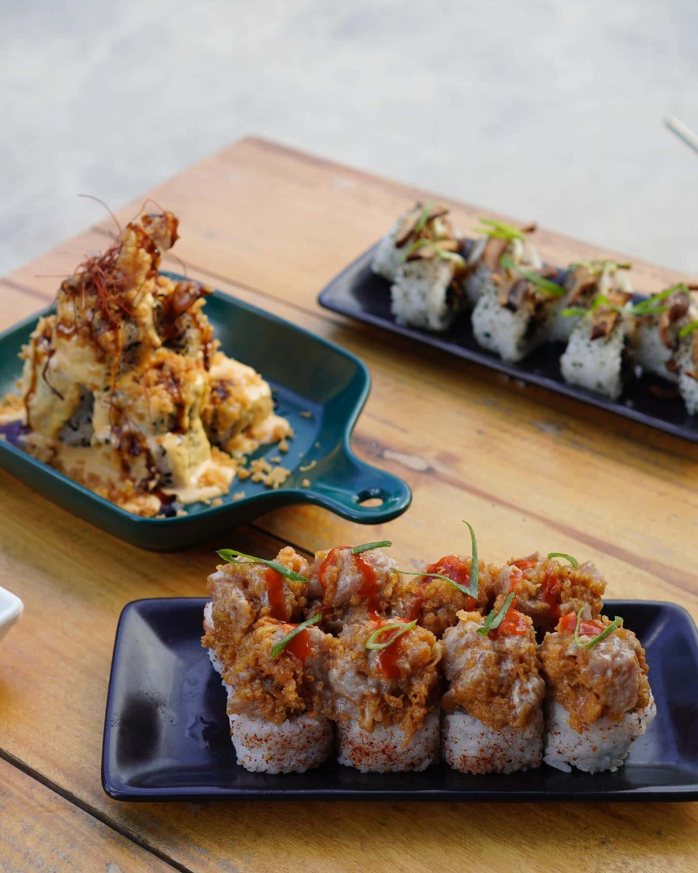 Tempura and sushi rolls served on dark plates