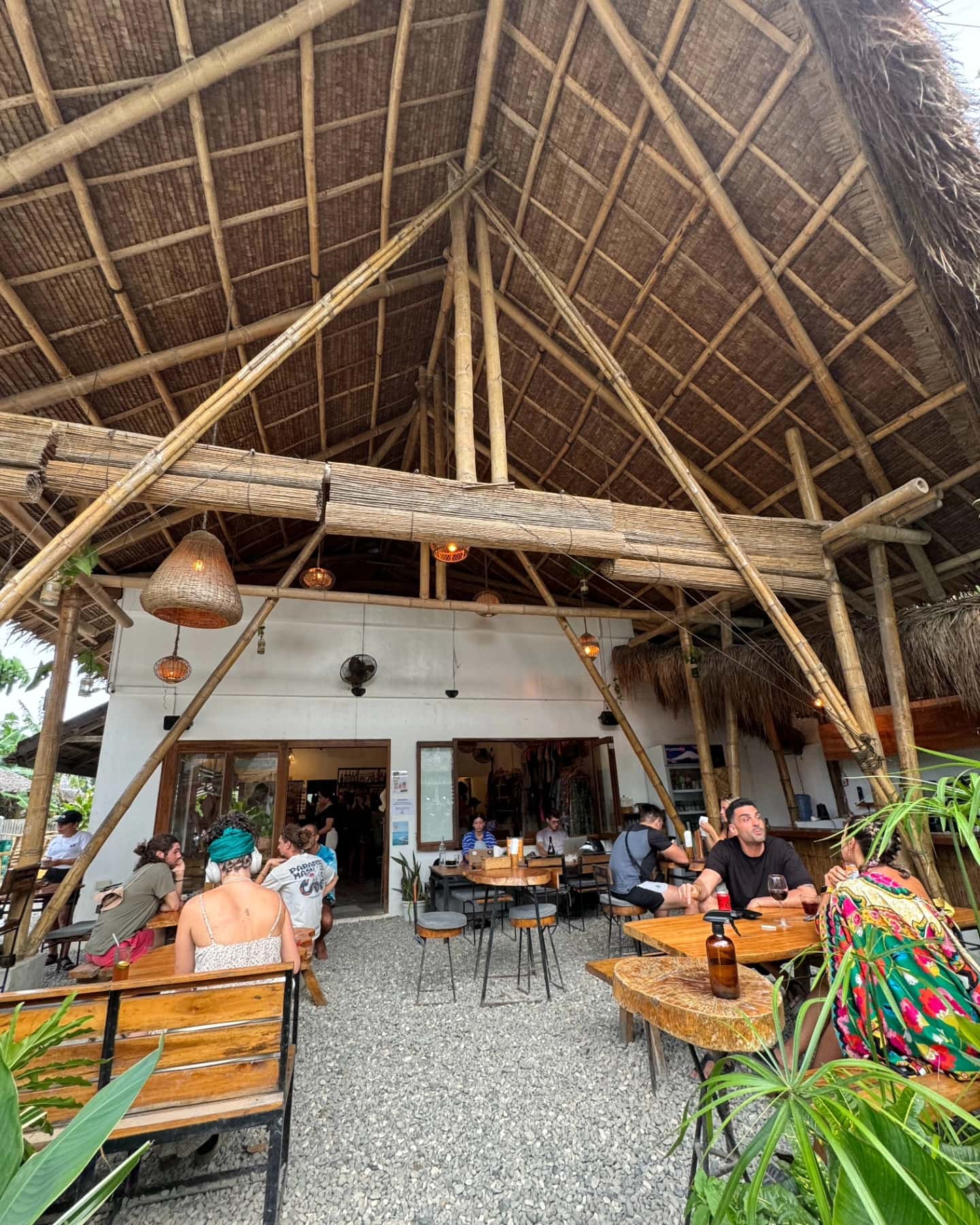 Diners under the high thatched roof of an open restaurant