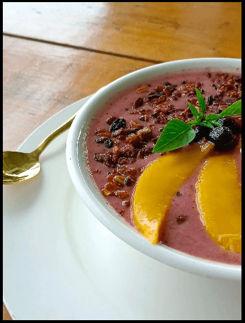 Purple porridge topped with mango and berries