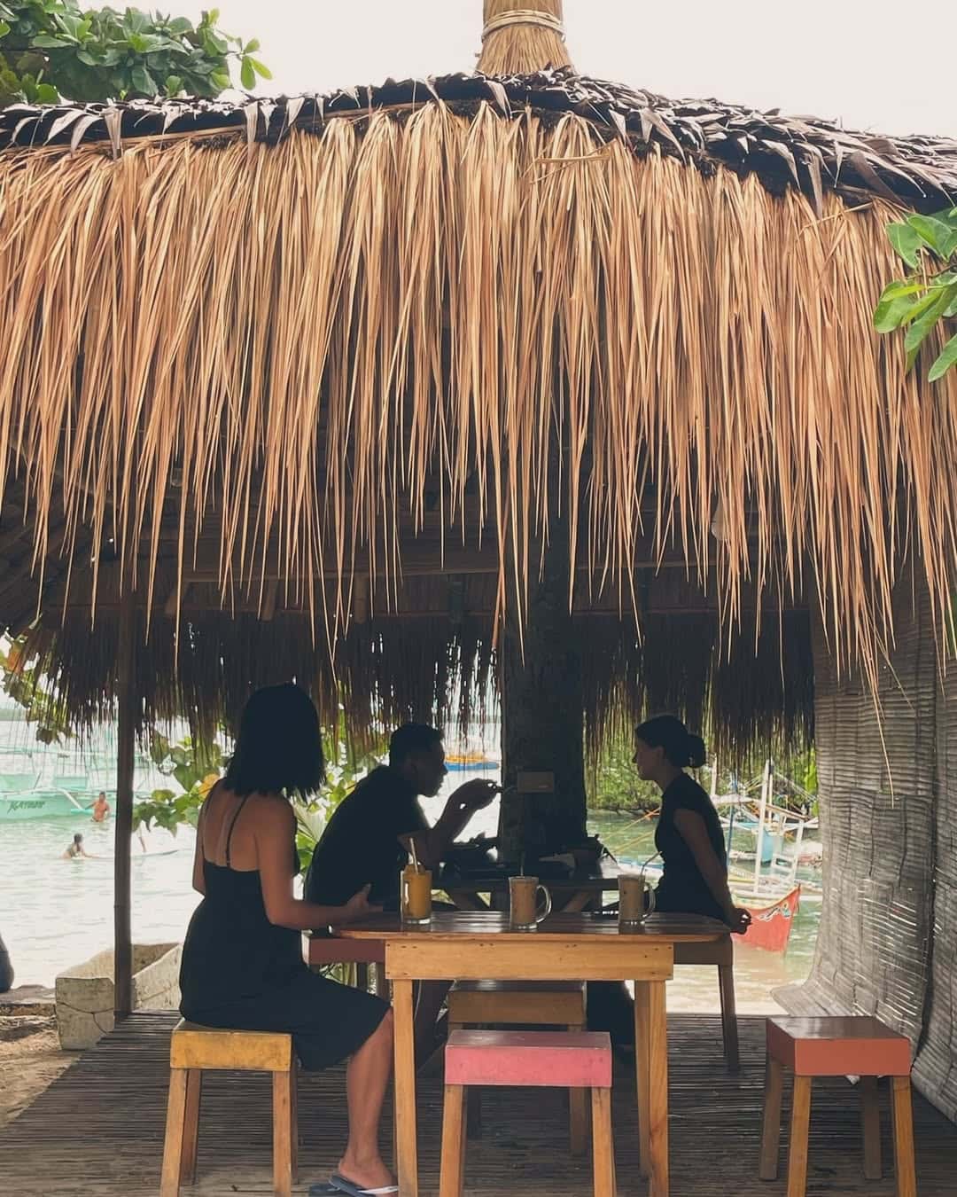 Silhouettes under a thatched beach shelter