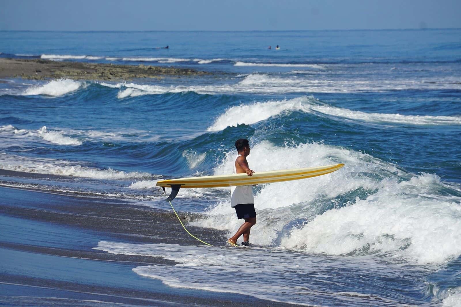 Surfer carrying a board into the shorebreak at San Juan, La Union