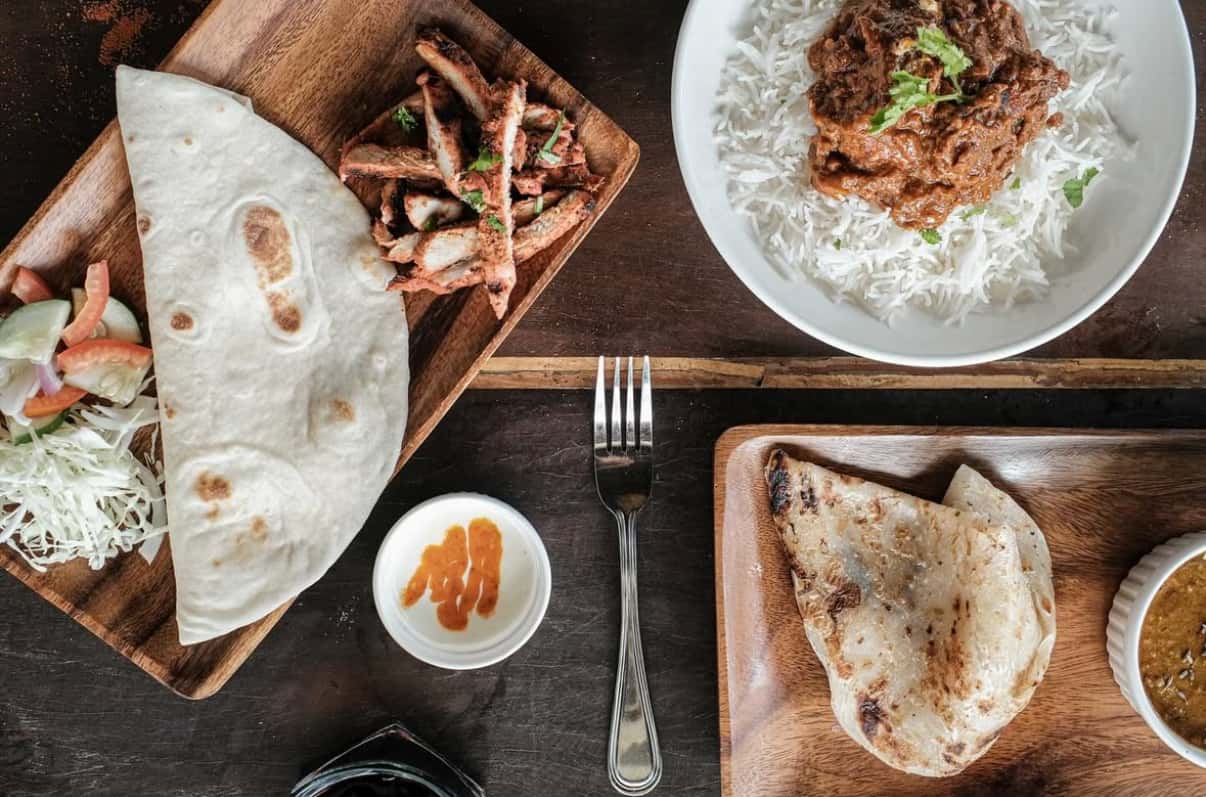 Naan bread, curry and rice set out on a wooden table