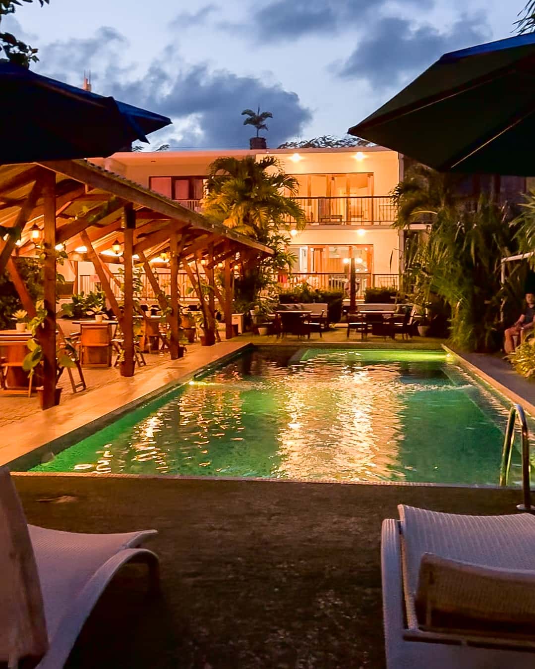 Pool lit up at dusk beside the bamboo building at Reef Beach Resort