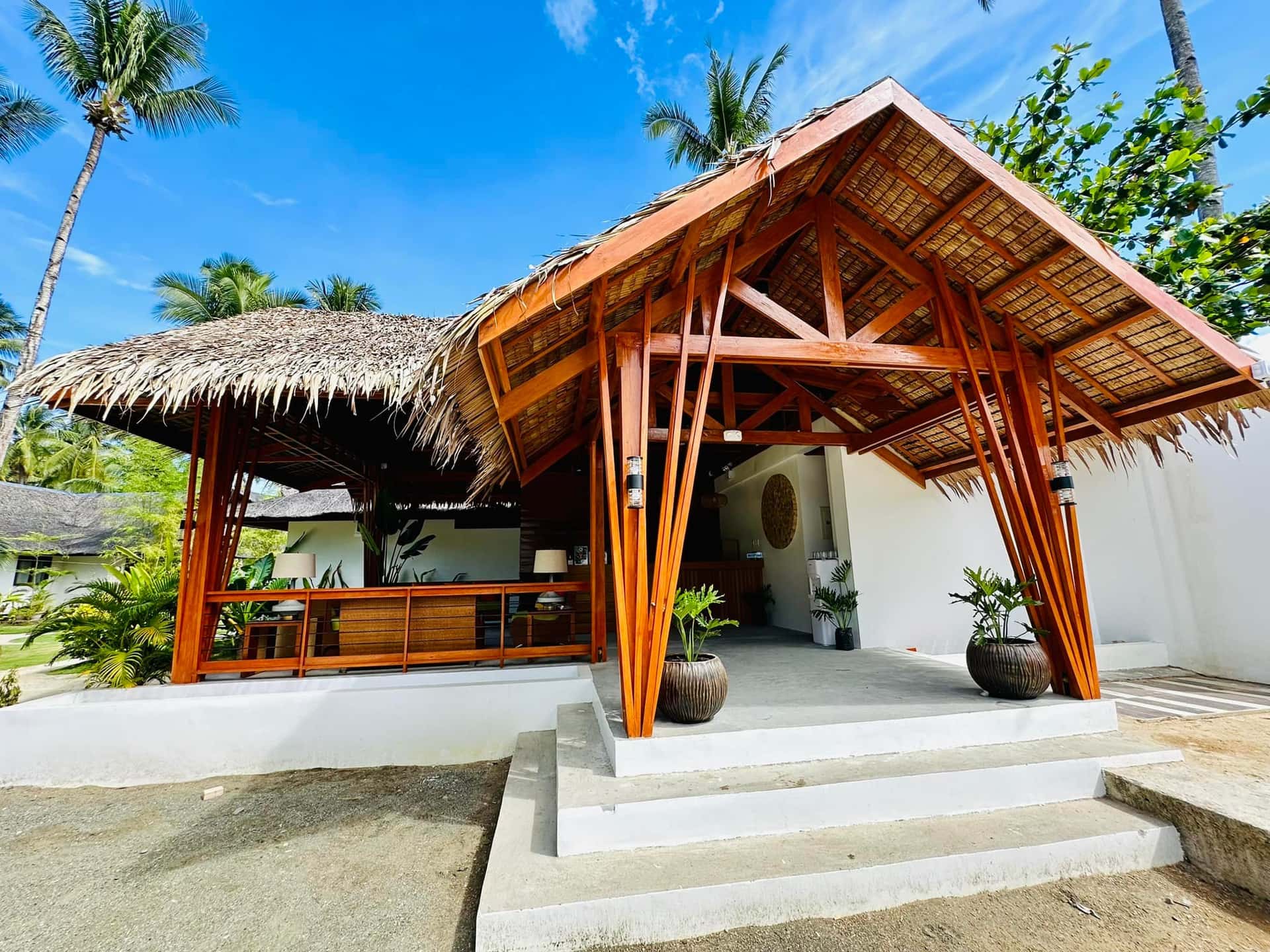 Thatched pavilion entrance to a white villa