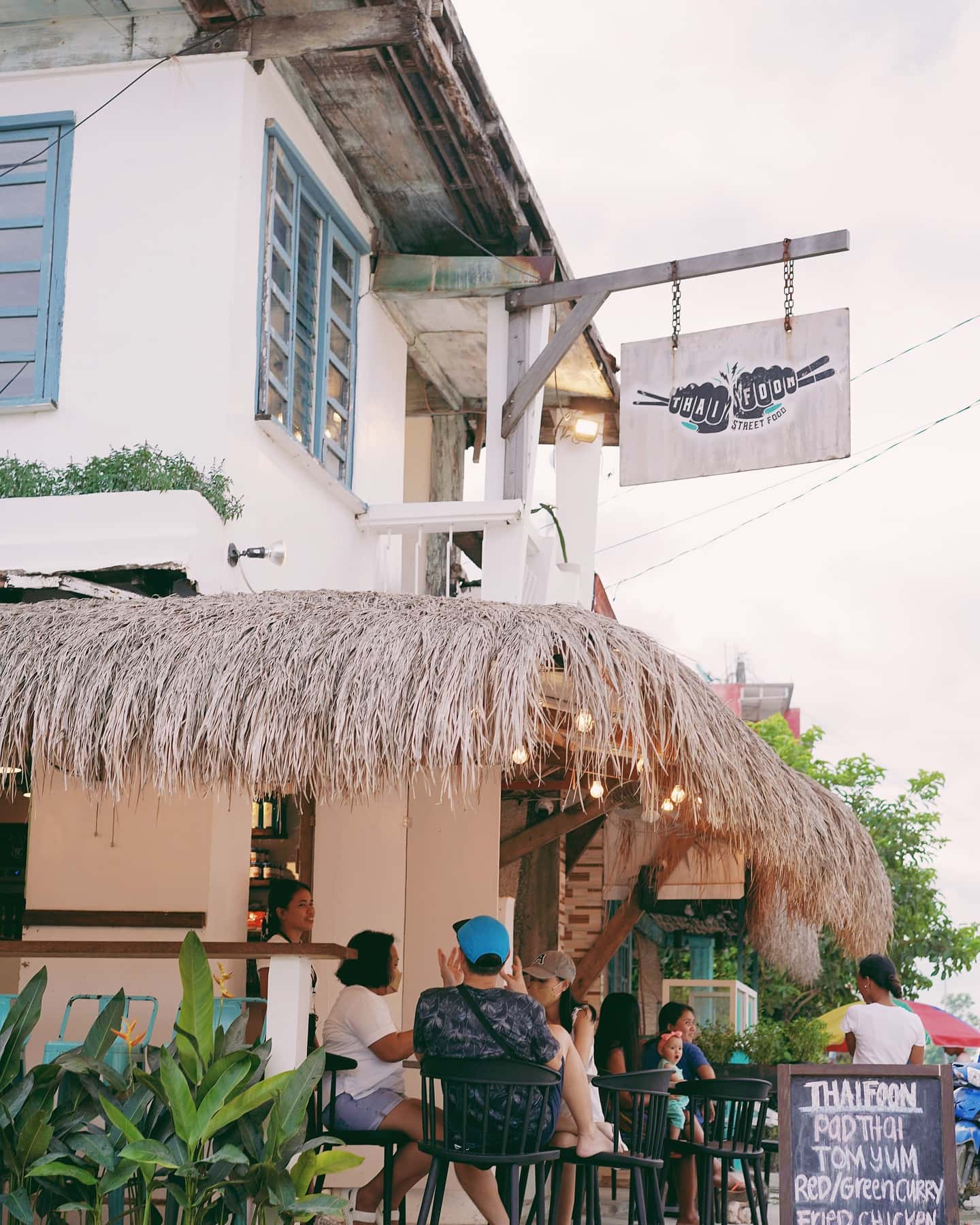 Thatched roof and a hanging sign outside a white building