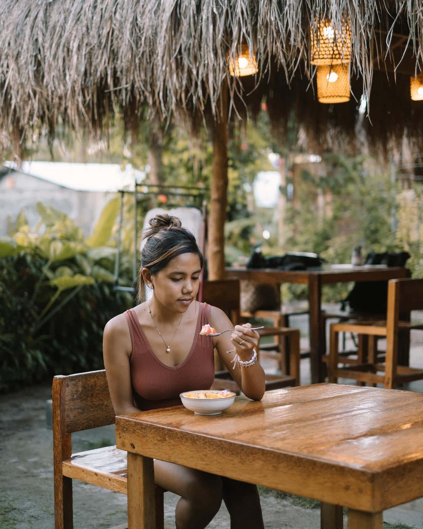 Woman eating breakfast at a cafe surrounded by plants