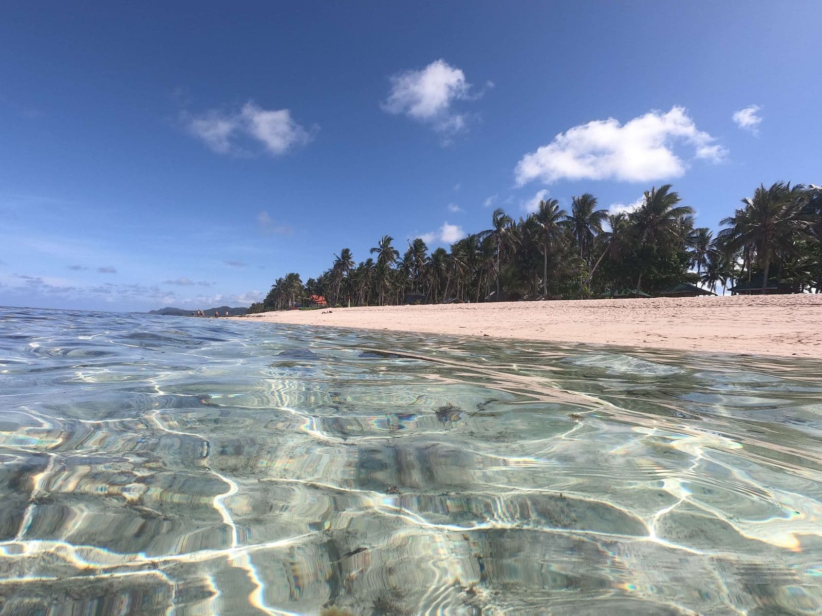Clear shallow water over white sand at Alegria Beach, Santa Monica, Siargao