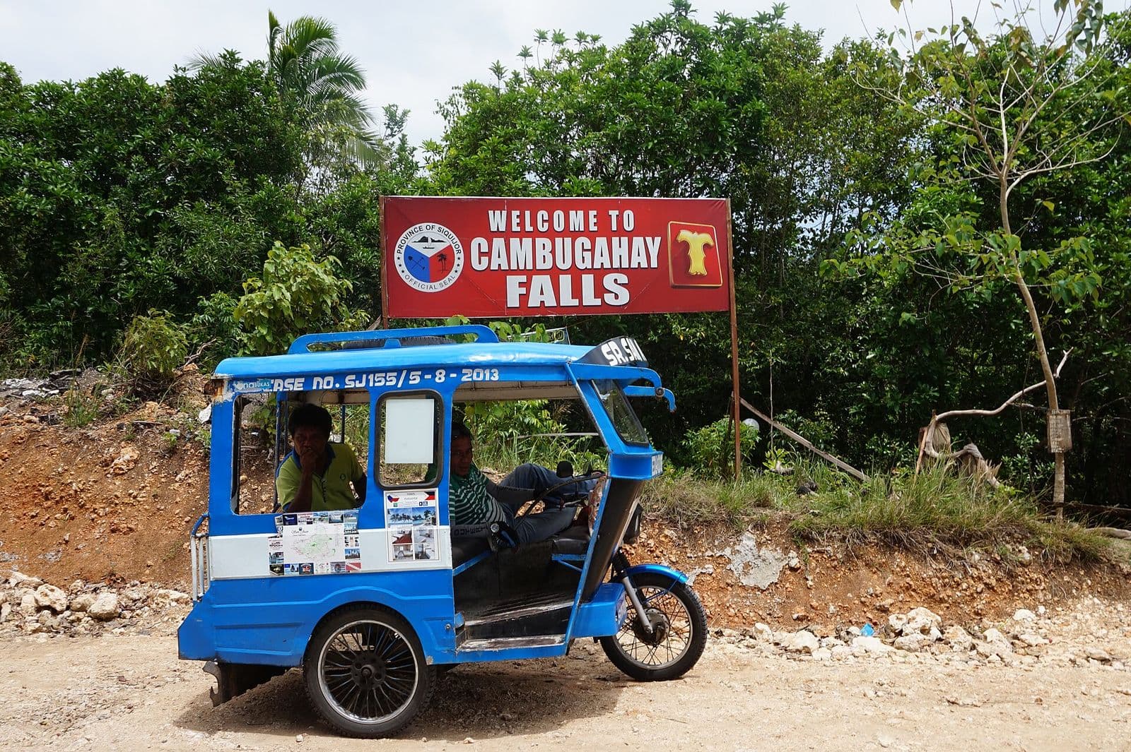 Tricycle at the Cambugahay Falls entrance sign in Lazi, Siquijor