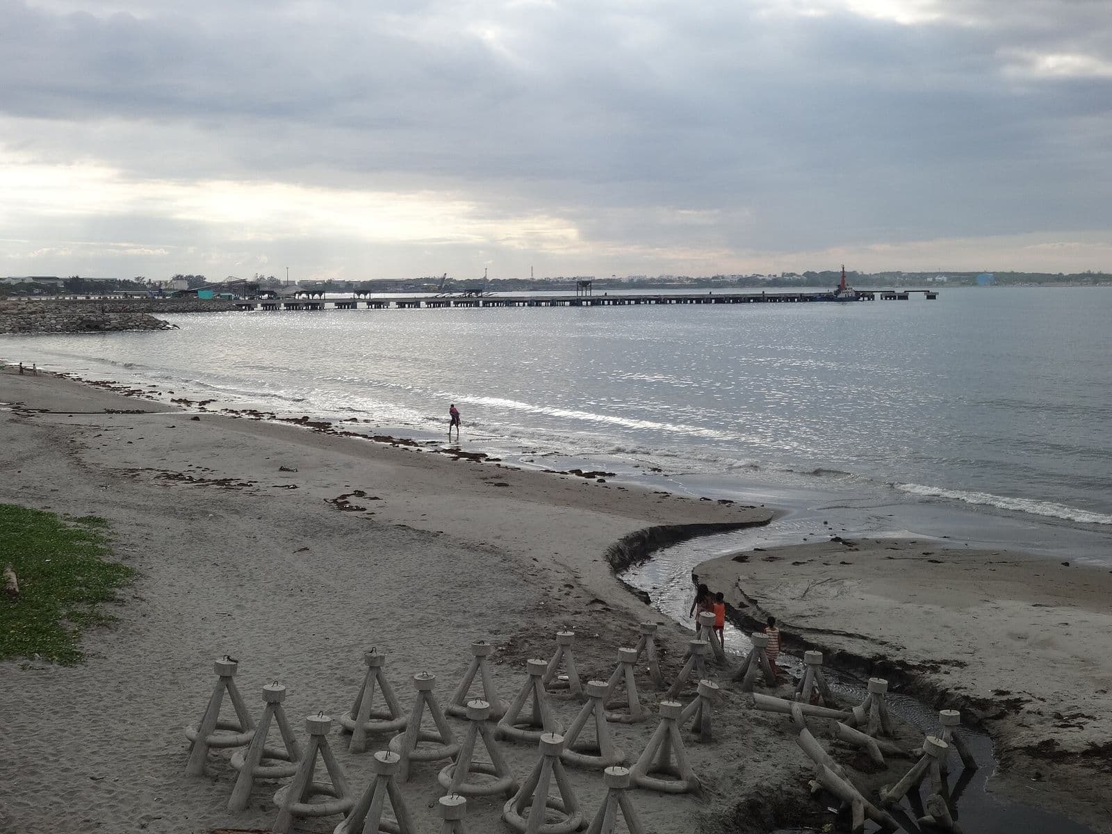 Grey-sand beach in San Fernando with Poro Point in the distance