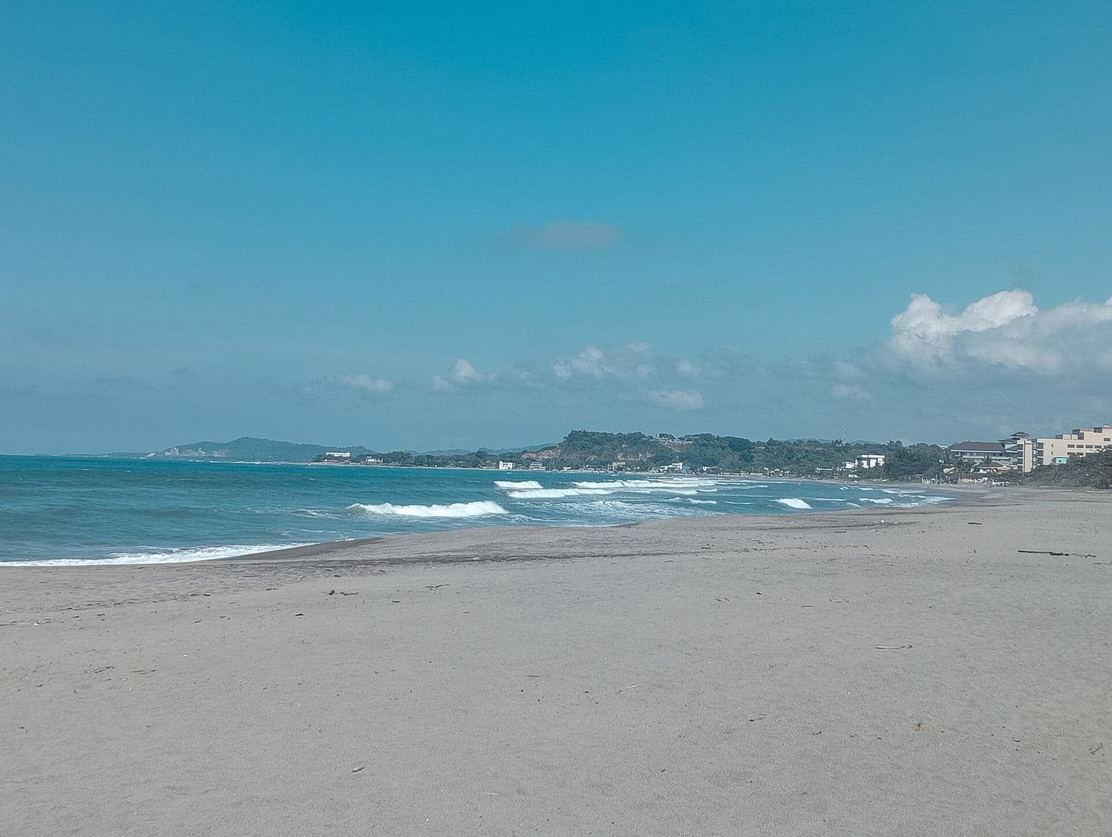 Waves rolling onto San Juan beach, La Union, with the coast curving north