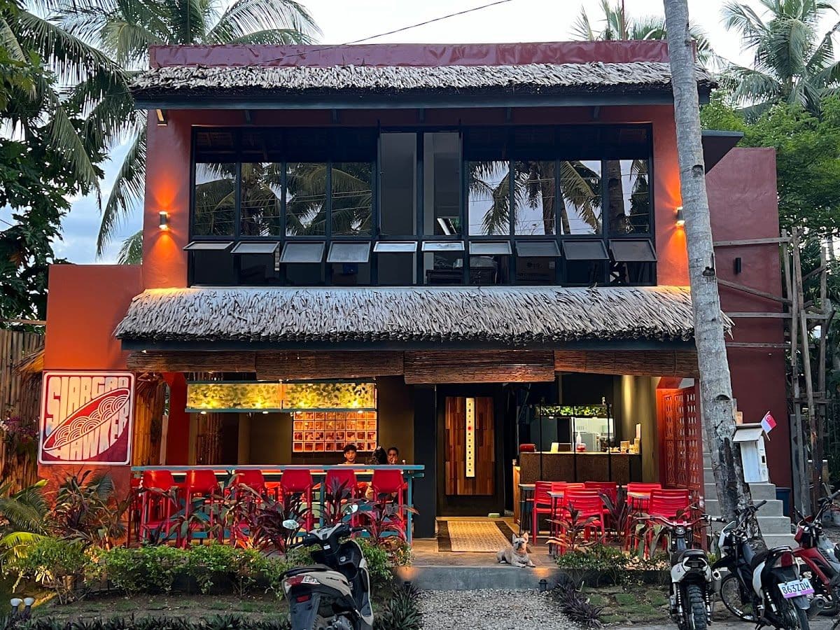 Evening exterior of Siargao Hawker restaurant with thatched roof and red signage, Catangnan, Siargao